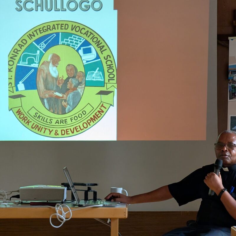 Pastor Mpora erklärt das Logo der St. Konrad School