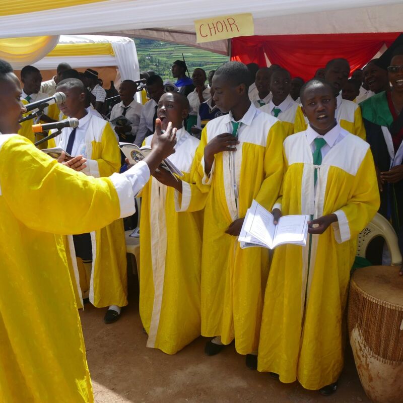 Der Schulchor in gelben Gewändern singt beim Festgottesdienst, daneben Trommeln